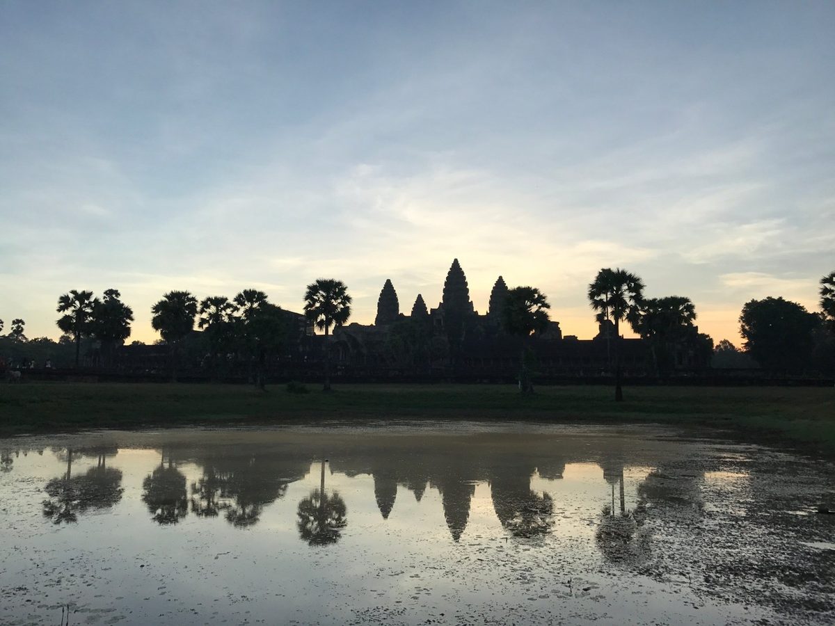 Angkor Wat silhouetted at sunrise, reflected in a pond