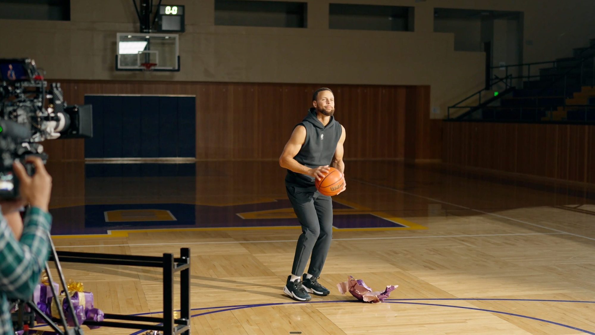 Steph Curry with a basketball on the gym set, a cinema camera in the foreground