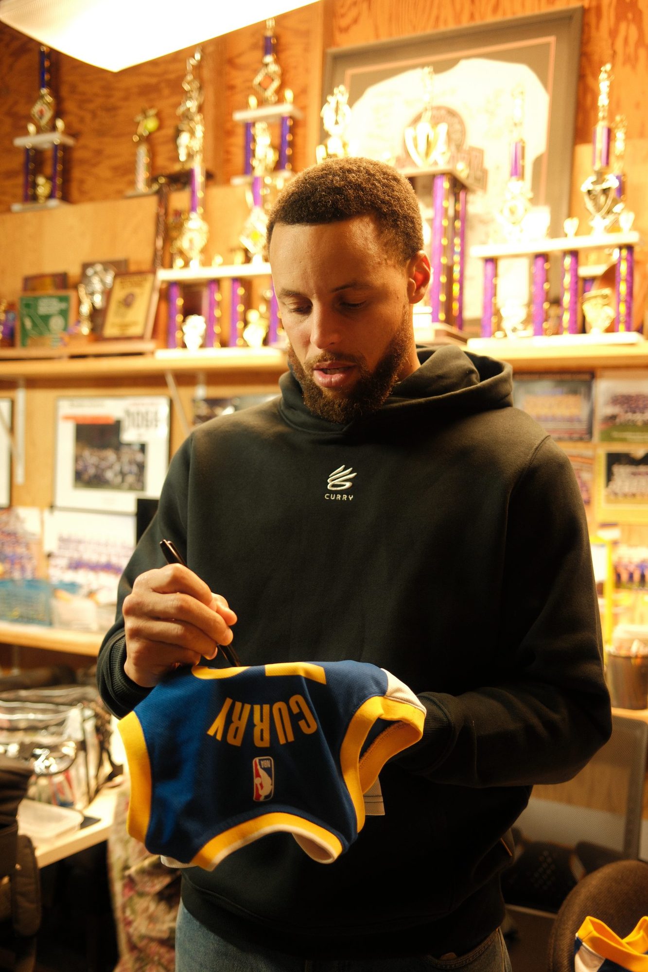 Steph Curry signing a jersey between takes