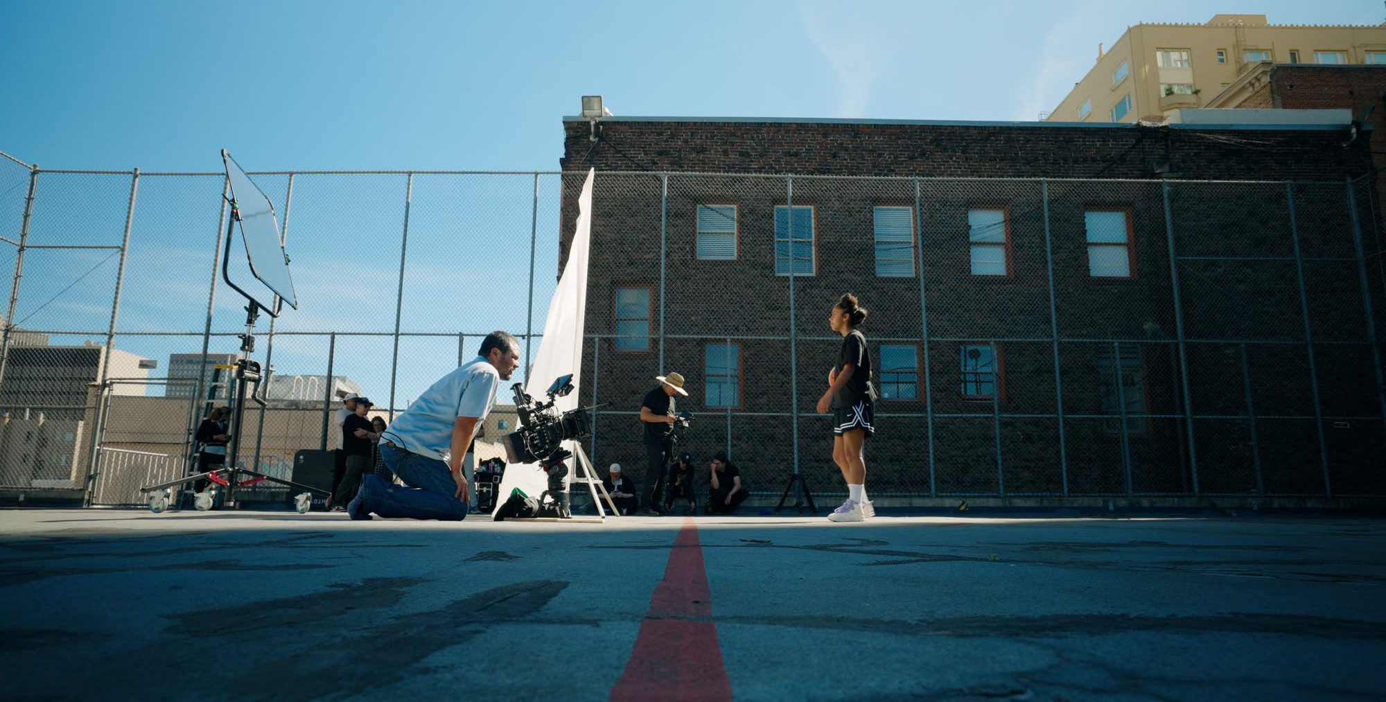 Crew filming a player on a rooftop basketball court